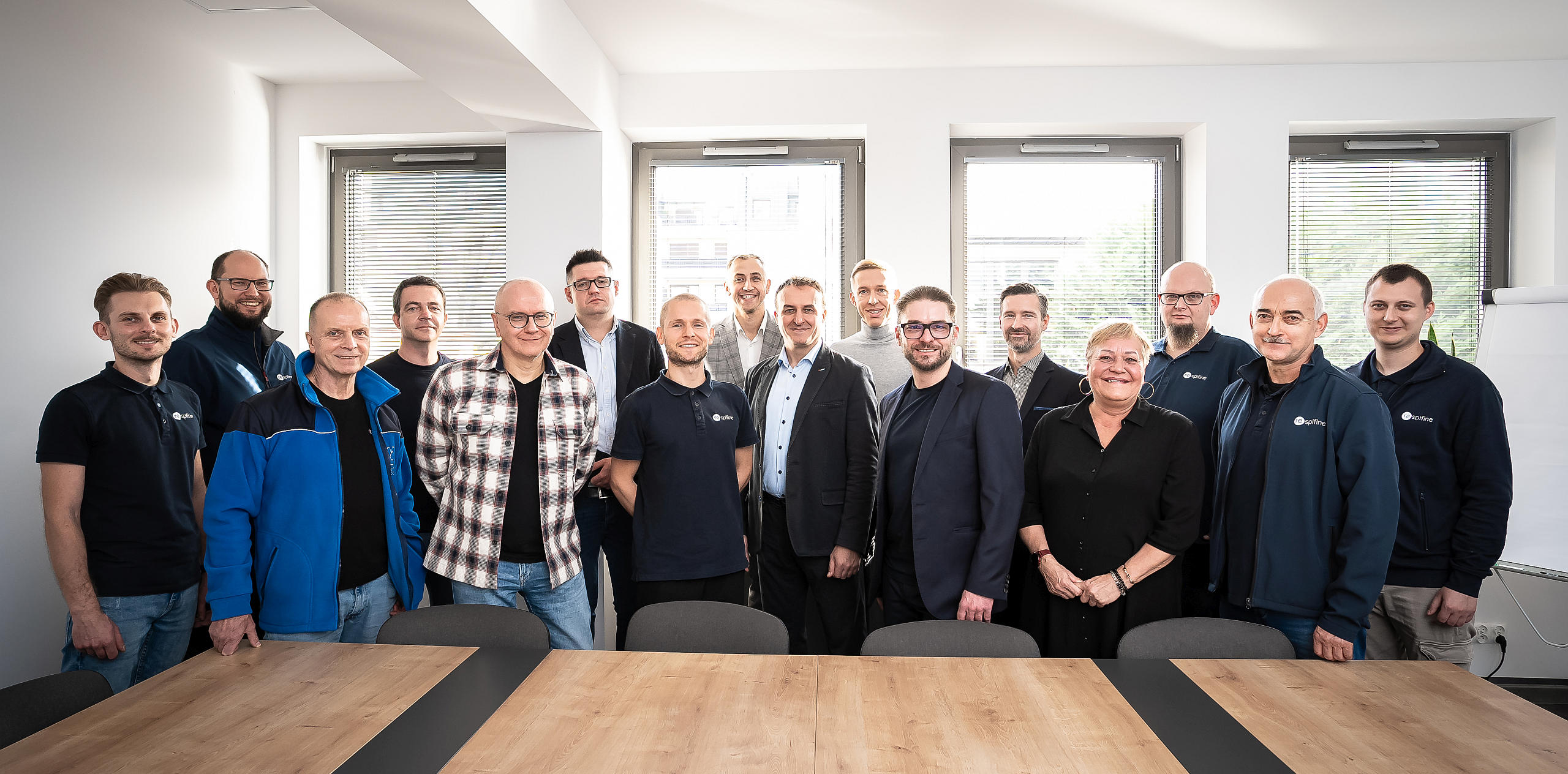 Grupa pracowników pozuje razem do wspólnego zdjęcia w jasnej sali konferencyjnej.