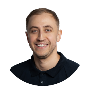 Mężczyzna w czarnej koszuli polo uśmiecha się, patrząc prosto w obiektyw.