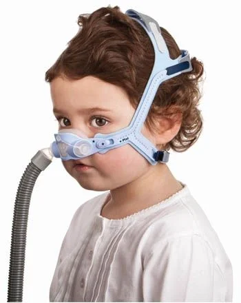 ResMed-PIXI.-Pediatric-CPAP-Mask.jpg Małe dziecko w masce tlenowej typu CPAP, patrzy w bok, tło białe.